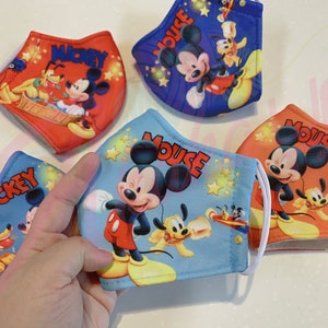 K&ouml;nnte beinhalten: Vier bunte Gesichtsmasken mit Mickey Mouse und Pluto. Die Masken sind aus Stoff und haben elastische Ohrschlaufen. Die Masken sind mit verschiedenen Designs bedruckt, darunter Mickey Mouse und Pluto in verschiedenen Posen. Die Masken sind alle in verschiedenen Farben, darunter Rot, Blau, Orange und Hellblau.