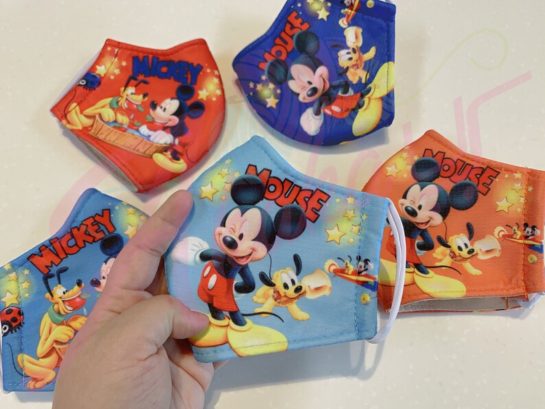 K&ouml;nnte beinhalten: Vier bunte Gesichtsmasken mit Mickey Mouse und Pluto. Die Masken sind aus Stoff und haben elastische Ohrschlaufen. Die Masken sind mit verschiedenen Designs bedruckt, darunter Mickey Mouse und Pluto in verschiedenen Posen. Die Masken sind alle in verschiedenen Farben, darunter Rot, Blau, Orange und Hellblau.