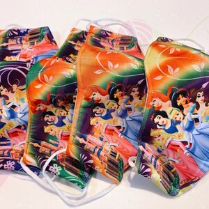 May include: Five colourful face masks featuring a pattern of Disney princesses, including Cinderella, Snow White, and Ariel. The masks have a white elastic band for wearing.