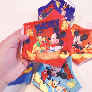 K&ouml;nnte beinhalten: Vier bunte Gesichtsmasken mit Mickey Mouse und Pluto. Die Masken sind rot, blau und orange mit wei&szlig;en Sternen und den Worten "Mickey Mouse" und "Mickey".