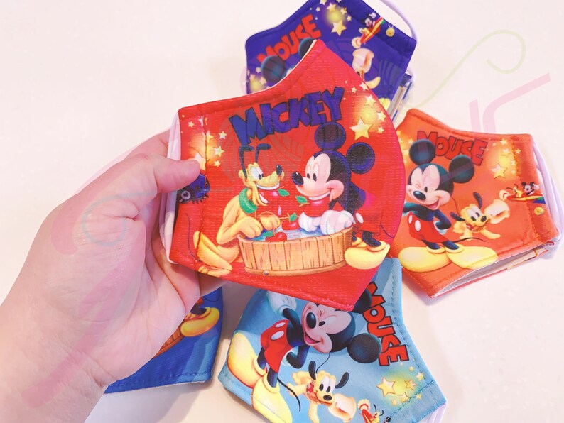 K&ouml;nnte beinhalten: Vier bunte Gesichtsmasken mit Mickey Mouse und Pluto. Die Masken sind rot, blau und orange mit wei&szlig;en Sternen und den Worten "Mickey Mouse" und "Mickey".