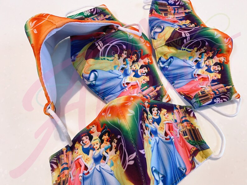 May include: Three colourful face masks featuring a variety of Disney princesses. The masks are made of a soft, breathable fabric and have adjustable ear loops. The princesses are depicted in a whimsical setting with castles and flowers.