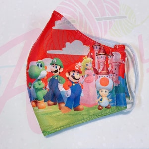 May include: A red, white, and blue face mask with a print of Mario, Luigi, Peach, Yoshi, and Toad. The mask features a castle and clouds in the background.