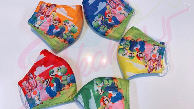 May include: Five colorful face masks with a Mario Brothers theme. The masks feature Mario, Luigi, Peach, Toad, and Yoshi. The masks are made of a soft, breathable fabric and are perfect for everyday use.