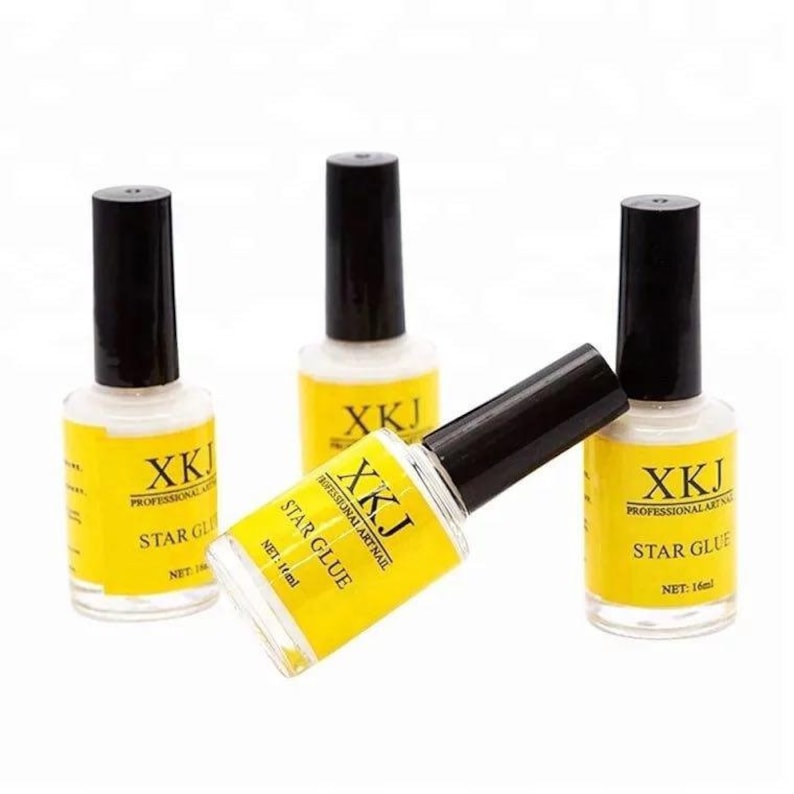 May include: Four bottles of nail glue are displayed against a white background. The bottles have black caps and yellow labels with the text "XKJ STAR GLUE PROFESSIONAL ART NAIL". Each bottle contains 16 ml of glue.