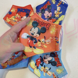 K&ouml;nnte beinhalten: Vier farbenfrohe Gesichtsmasken mit Mickey Mouse und Pluto. Die Masken sind aus Stoff und haben elastische Ohrschlaufen. Die Masken sind mit verschiedenen Designs bedruckt, darunter Mickey Mouse, Pluto und Sterne.