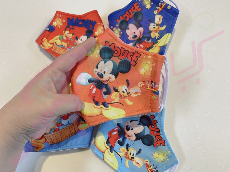 K&ouml;nnte beinhalten: Vier farbenfrohe Gesichtsmasken mit Mickey Mouse und Pluto. Die Masken sind aus Stoff und haben elastische Ohrschlaufen. Die Masken sind mit verschiedenen Designs bedruckt, darunter Mickey Mouse, Pluto und Sterne.