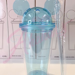 May include: A clear blue plastic tumbler with a lid and two ears shaped like Mickey Mouse. The tumbler has a straw and is labeled "450ML" and "Made in China".