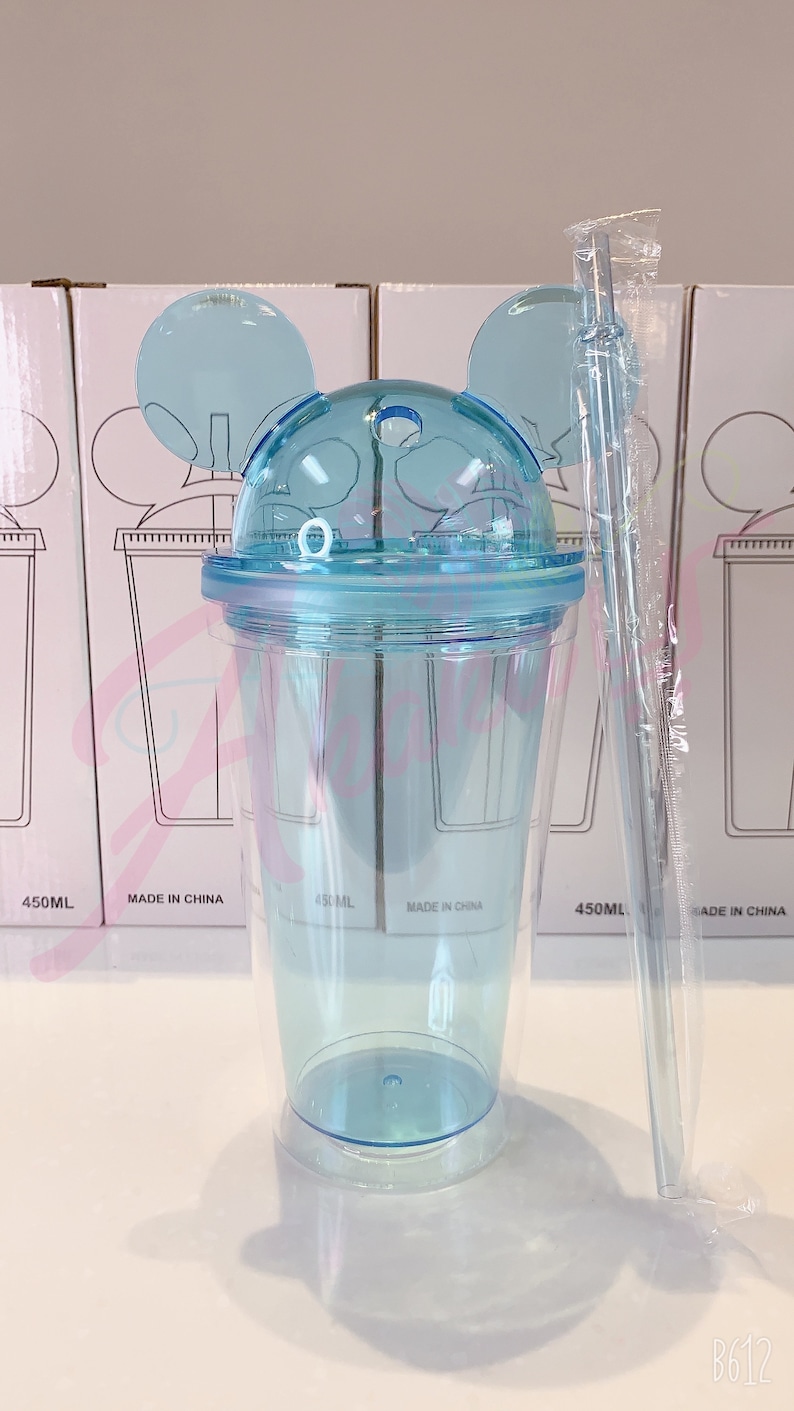 May include: A clear blue plastic tumbler with a lid and two ears shaped like Mickey Mouse. The tumbler has a straw and is labeled "450ML" and "Made in China".