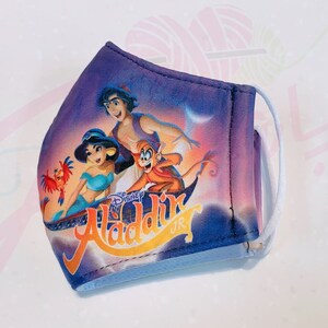 May include: A purple face mask with a Disney Aladdin Jr. design featuring Aladdin, Jasmine, and Abu on a magic carpet. The mask has white elastic ear loops.