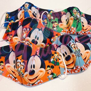 May include: A set of five colorful face masks featuring Mickey Mouse and other Disney characters. The masks are made of a soft, breathable fabric and have adjustable ear loops.