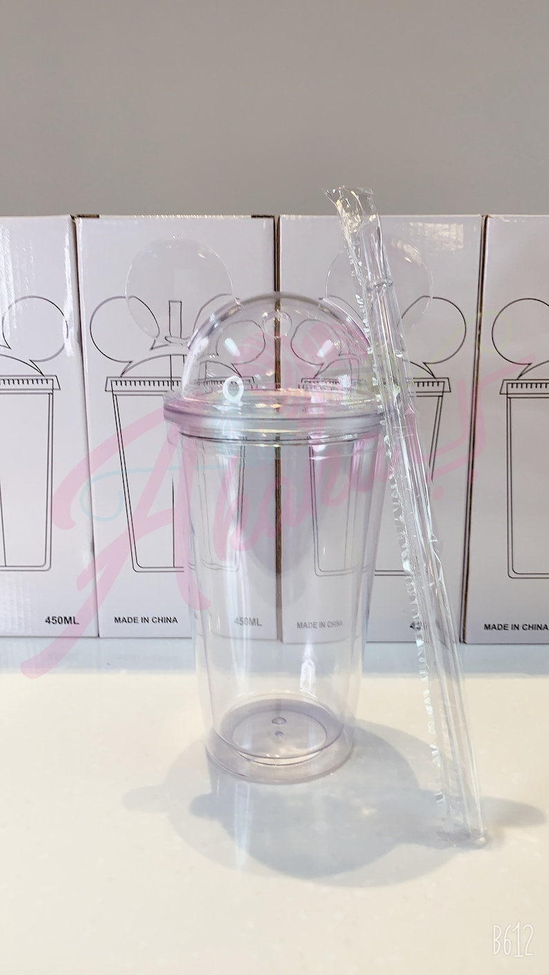 May include: Clear plastic cup with a dome lid and a straw. The cup has a Mickey Mouse ear design on the lid. The cup is 450 ml and made in China.