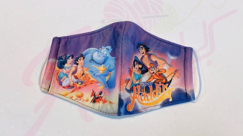 May include: A purple, blue and yellow face mask with a Disney Aladdin Jr. design. The mask features images of Aladdin, Jasmine, Abu and Genie.
