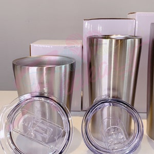 Puede incluir: Dos vasos de acero inoxidable con tapas. Los vasos son plateados y tienen un acabado cepillado. Las tapas son de pl&aacute;stico transparente con un sello de silicona.