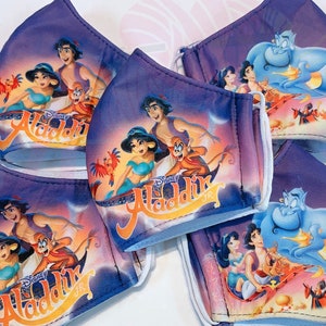 May include: Five purple face masks featuring a printed image of Aladdin and Jasmine on a magic carpet. The masks have white elastic ear loops.