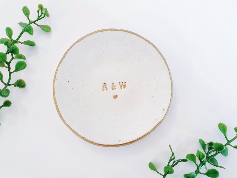 May include: White ceramic ring dish with a gold rim and the initials "A & W" with a small heart in between.