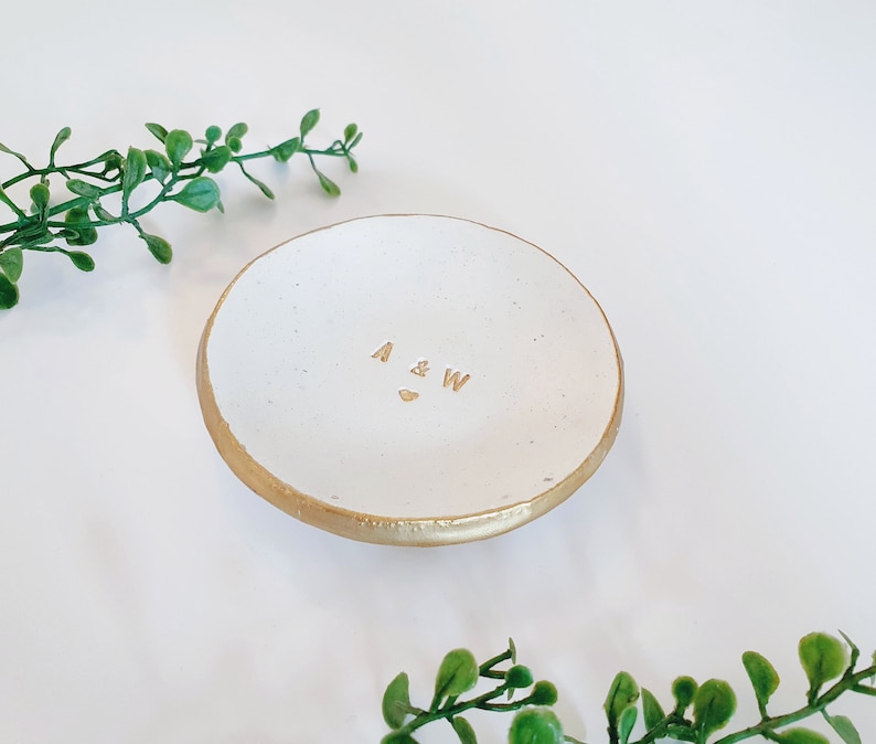 May include: White ceramic ring dish with a gold rim and the initials "A & W" inscribed in gold lettering.