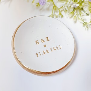May include: White ceramic ring dish with a gold rim. The dish has the initials "S & Z" and the date "21.08.2023" inscribed in gold lettering.
