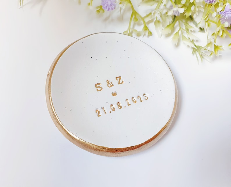 May include: White ceramic ring dish with a gold rim. The dish has the initials "S & Z" and the date "21.08.2023" inscribed in gold lettering.