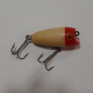 May include: A white and red fishing lure with three treble hooks.