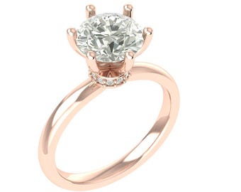 Puede incluir: Anillo de compromiso de oro rosa con una gema grande, redonda y transparente. El anillo presenta un engaste clásico de seis puntas y una banda delicada. Pequeñas piedras de acento alrededor de la base de la piedra principal.