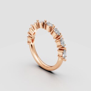 Puede incluir: Anillo de oro rosa con una serie de diamantes de talla ovalada. Los diamantes están engastados en garras individuales a lo largo de la banda, creando un brillo continuo. El tono cálido del anillo contrasta con las piedras claras y brillantes.