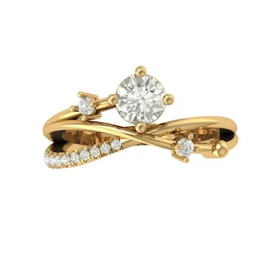 Puede incluir: Un anillo dorado con un diseño único y fluido. El anillo presenta una piedra preciosa grande, redonda y transparente en el centro, rodeada de piedras preciosas más pequeñas y transparentes. Pequeñas piedras preciosas adicionales están engastadas a lo largo de la banda.