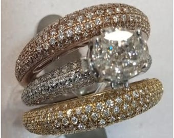 May include: Three diamond rings. The top ring is rose gold, the middle ring is silver, and the bottom ring is gold. The rings are encrusted with small diamonds. The center ring has a large, square-cut diamond.