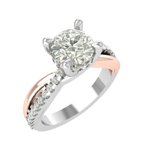 Puede incluir: Un anillo de compromiso de plata y oro rosa con una piedra preciosa grande, redonda y transparente. La banda presenta pequeñas piedras de acento y un diseño retorcido. El anillo está sobre un fondo blanco.