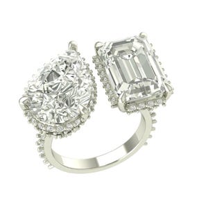 Può includere: Un anello d'argento con due grandi gemme trasparenti: una pietra a forma di pera e una pietra taglio smeraldo. Entrambe le pietre sono circondate da pietre più piccole, con un gambo dettagliato.