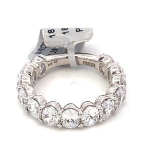 Puede incluir: Un anillo de plata con una fila continua de piedras preciosas claras de talla ovalada. El anillo está sobre un fondo blanco. Una etiqueta está sujeta al anillo.