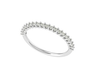 Könnte beinhalten: Ein zarter, silberfarbener Ring mit einer Reihe kleiner, funkelnder Diamanten. Die Diamanten sind gleichmäßig über die Oberseite des Rings verteilt und bilden ein durchgehendes, schimmerndes Band. Der Ring ist glatt und poliert.