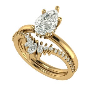 Puede incluir: Anillo de compromiso dorado con un diamante central en forma de pera. La banda presenta un diseño de vástago dividido con diamantes de acento más pequeños y una fila de piedras engastadas en pavé. Sobre fondo blanco.