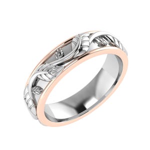 Puede incluir: Un anillo de dos tonos con un diseño floral. El anillo presenta una banda plateada con un borde de oro rosa y un patrón de hojas detallado. Las hojas son plateadas y están colocadas contra la banda de oro rosa.