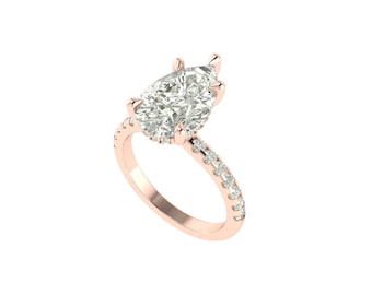 May include: Rose gold engagement ring with a pear-cut diamond. The band is embellished with small diamonds. The ring's design is elegant and classic, suitable for a special occasion. The ring is a beautiful piece of jewellery.