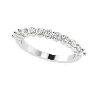 Puede incluir: Un anillo de plata con una fila de diamantes redondos y brillantes. Los diamantes están engastados en un patrón en zigzag a lo largo de la banda. El anillo se muestra sobre un fondo blanco, resaltando su metal pulido y el brillo de las piedras preciosas.