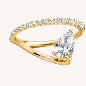 Puede incluir: Un anillo de oro con un diamante en forma de pera y una banda con pequeños diamantes. El diseño del anillo presenta una caña dividida que se curva alrededor del dedo, creando un aspecto moderno y elegante.