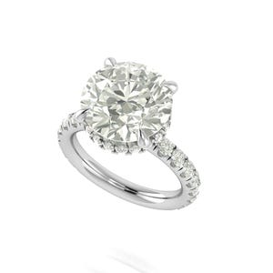 May include: A dazzling engagement ring featuring a large, round-cut diamond as the centerpiece. The band is crafted from polished silver and is adorned with smaller diamonds, enhancing the ring's brilliance. The ring is set against a clean white background.