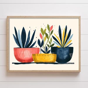 May include: A framed art print featuring three potted plants. The left plant has dark blue leaves in a coral pot. The center plant has green and pink leaves in a yellow pot. The right plant has blue and yellow leaves in a dark blue pot.