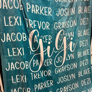The image is a large blue blanket with the names of several people printed on it in white text.