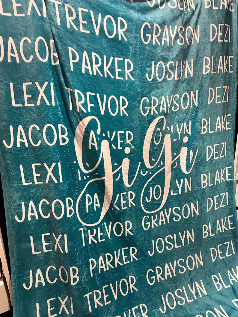 The image is a large blue blanket with the names of several people printed on it in white text.