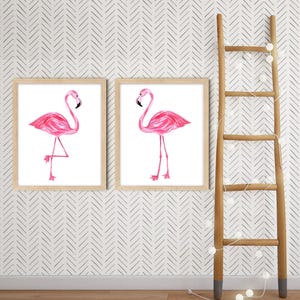 May include: Two framed prints featuring pink flamingo illustrations. The flamingos are depicted in a watercolor style against a white background. A wooden ladder with decorative lights is positioned to the right of the prints.