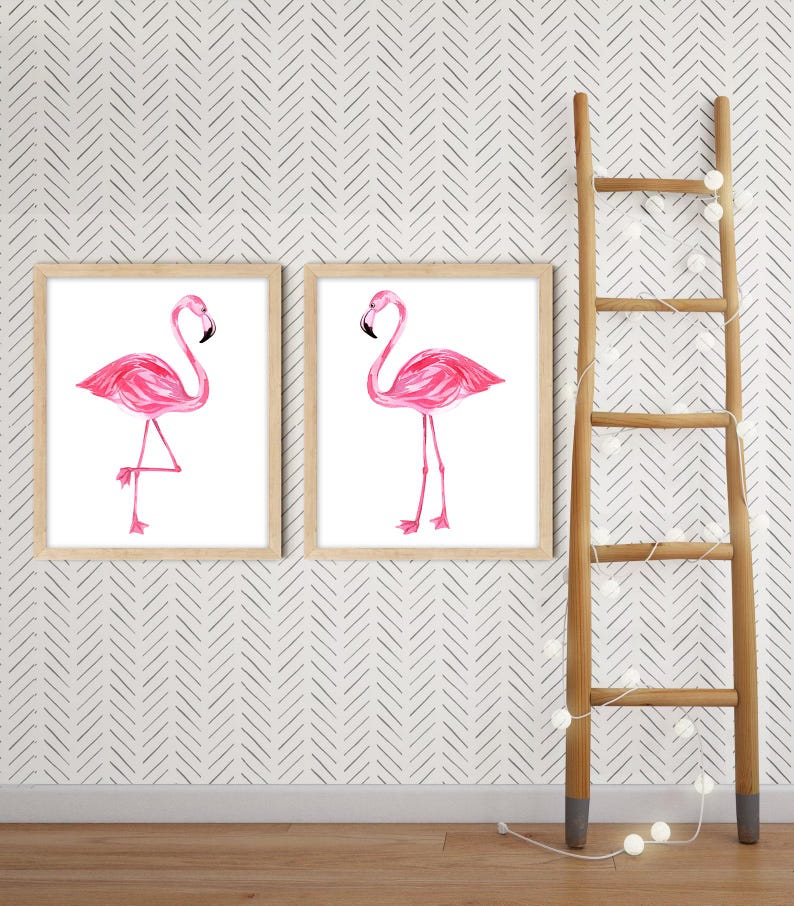 May include: Two framed prints featuring pink flamingo illustrations. The flamingos are depicted in a watercolor style against a white background. A wooden ladder with decorative lights is positioned to the right of the prints.