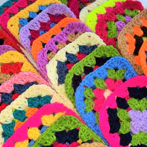 May include: A collection of colourful crocheted granny squares in various colours, including pink, blue, green, yellow, and orange. The squares are arranged in a fan shape, with the largest square at the bottom and the smallest square at the top.
