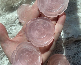 May include: Five pink rose quartz crystal carvings in the shape of roses. The carvings are smooth and polished.