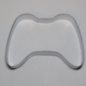 May include: A silver metal cookie cutter shaped like a video game controller.