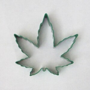 May include: Green metal cookie cutter shaped like a marijuana leaf.