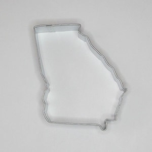 May include: A silver metal cookie cutter shaped like the state of Georgia.