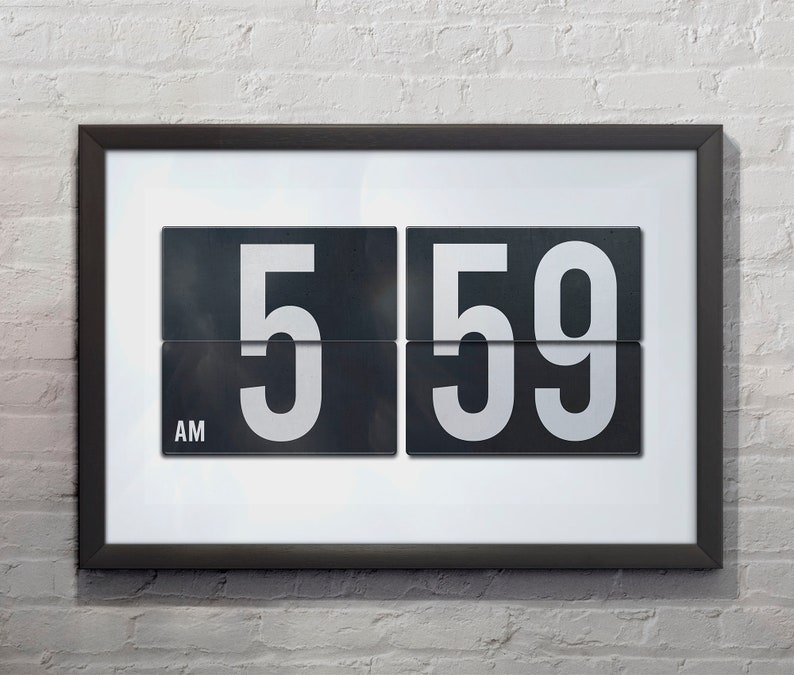 May include: A black framed clock with white numbers displays 5:59 AM. The clock has a white background and a black frame.