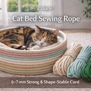 Könnte beinhalten: Eine schlafende Katze liegt in einem runden Katzenbett mit einem gestreiften Design in Pastellfarben. Daneben liegen drei Bündel 6-7 mm starker und formstabiler Kordel in Creme, Türkis und Grün. Der Text "cafuné Cat Bed Sewing Rope" ist sichtbar.
